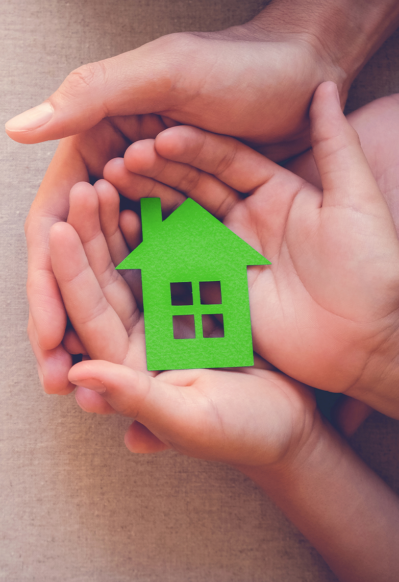 Hands holding green paper house