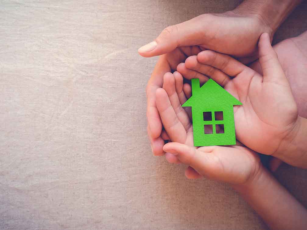 Hands holding green paper house