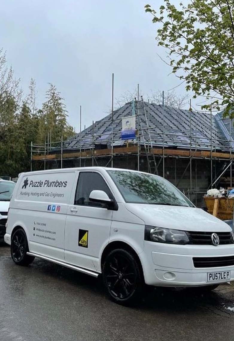 Puzzle Plumbers vans in front of new build house