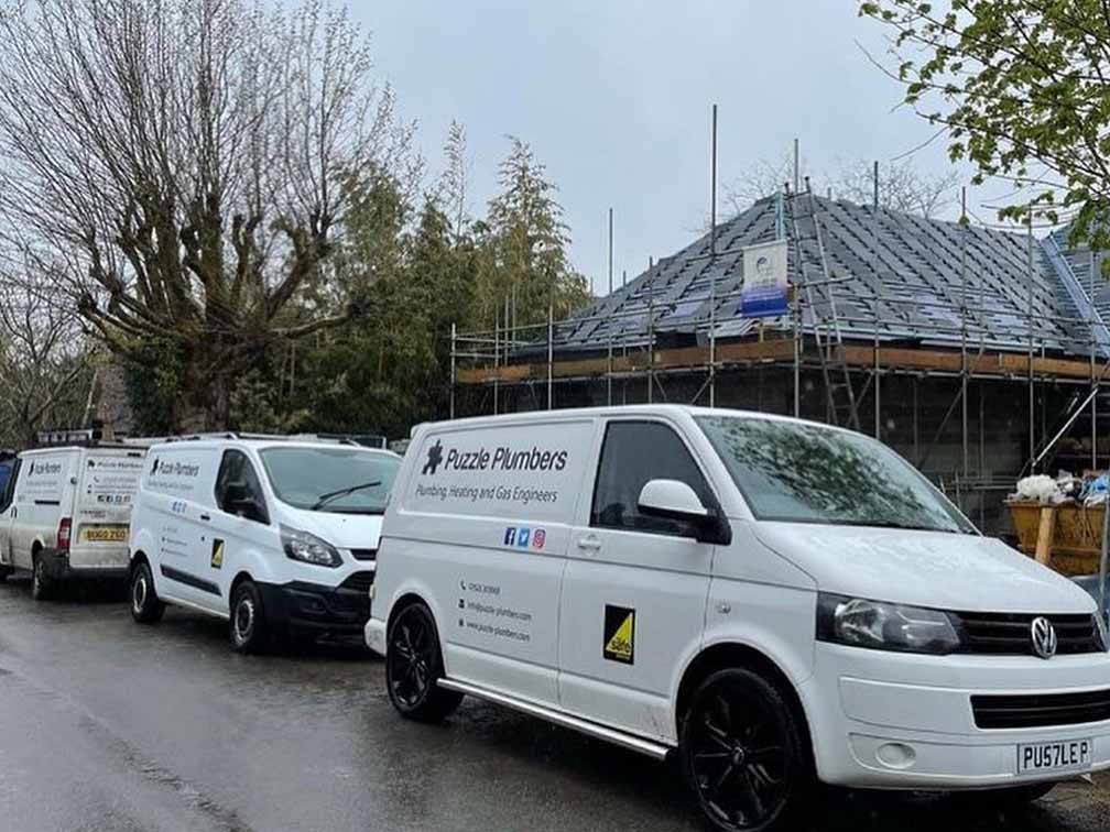 Puzzle Plumbers vans in front of new build house